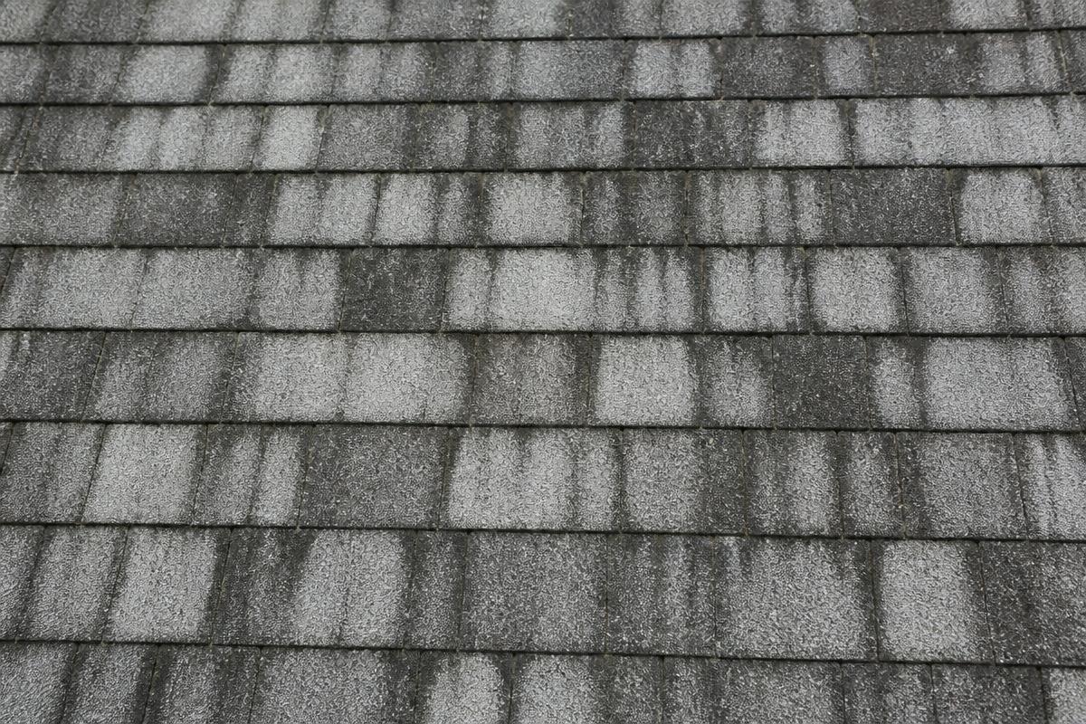 Dark organic streaks running down asphalt roof shingles